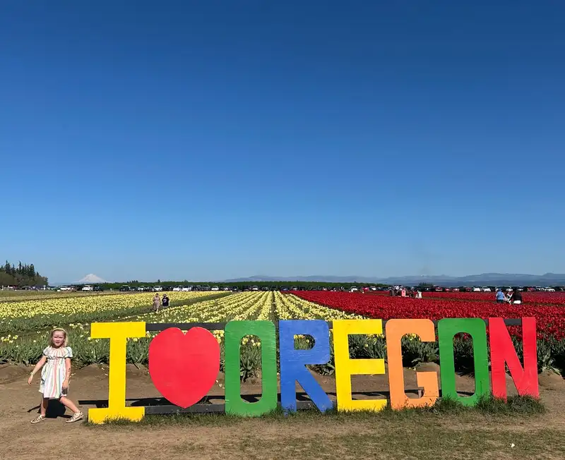 Juni at the tulip festival, with Oregon fields and mountains behind her